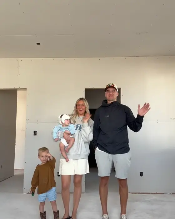 A family waving inside their home while it is being built